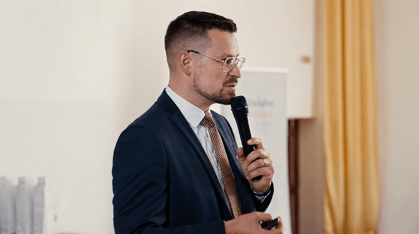 Řečník s mikrofonem na firemní akci 4FIN